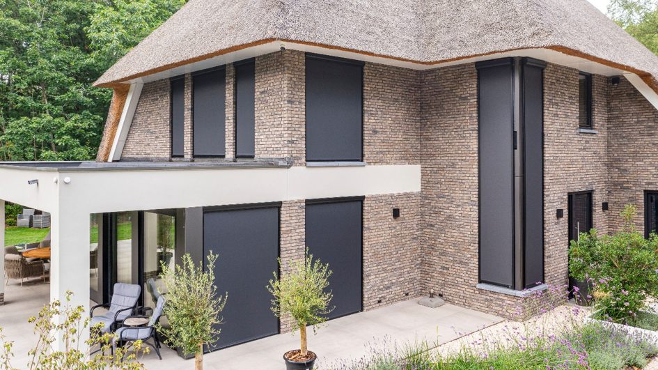 Screens aan een rietgedekte villa, gemonteerd door Exact Zonwering