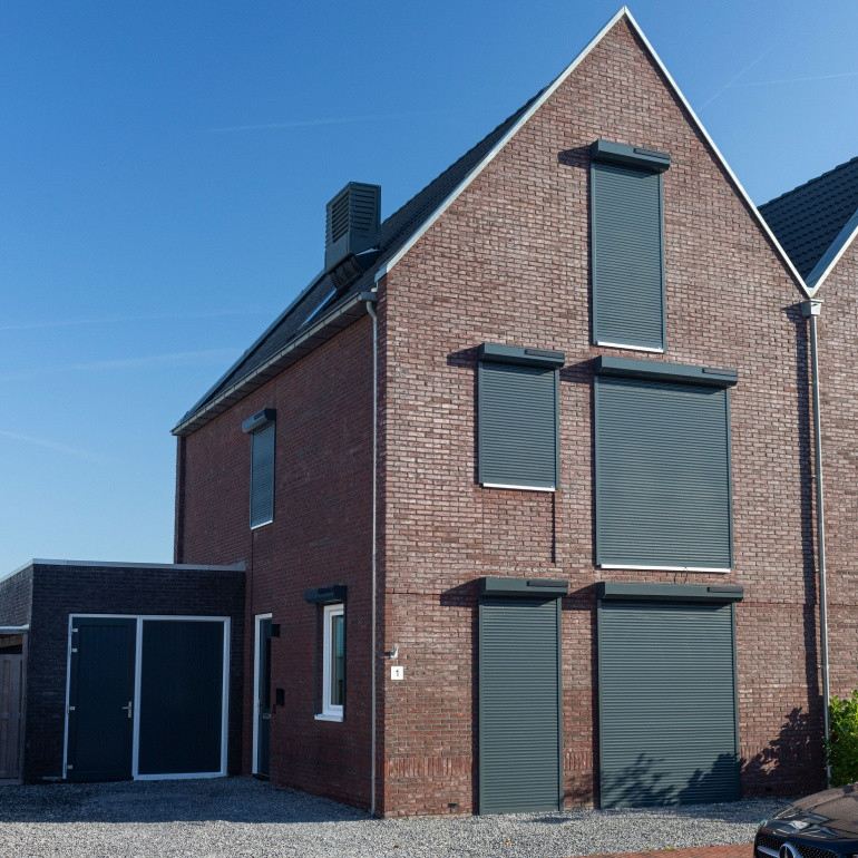 Meerdere antraciet rolluiken aan een bakstenen woning, gemonteerd door Exact Zonwering